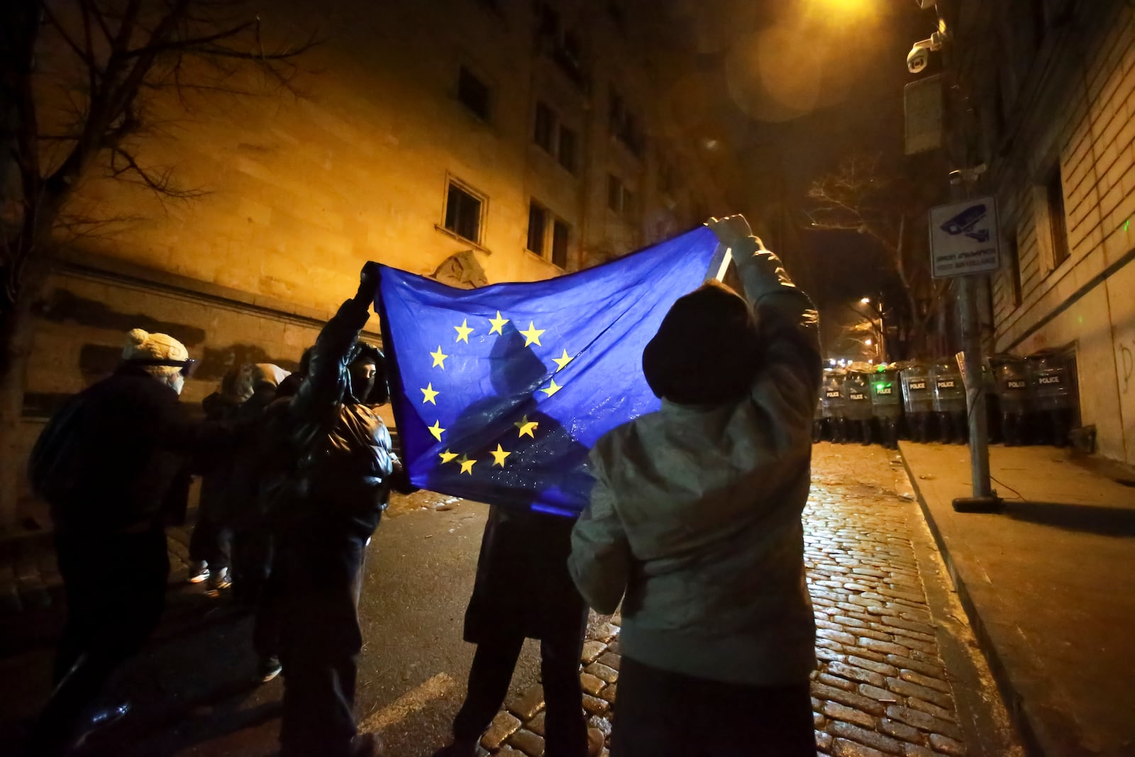 FILE - Demonstrators hold a European Union flag in front of police in Tbilisi, Georgia, on Dec. 2, 2024, while rallying outside parliament against the government's decision to suspend negotiations on joining the EU. (AP Photo/Zurab Tsertsvadze, File)