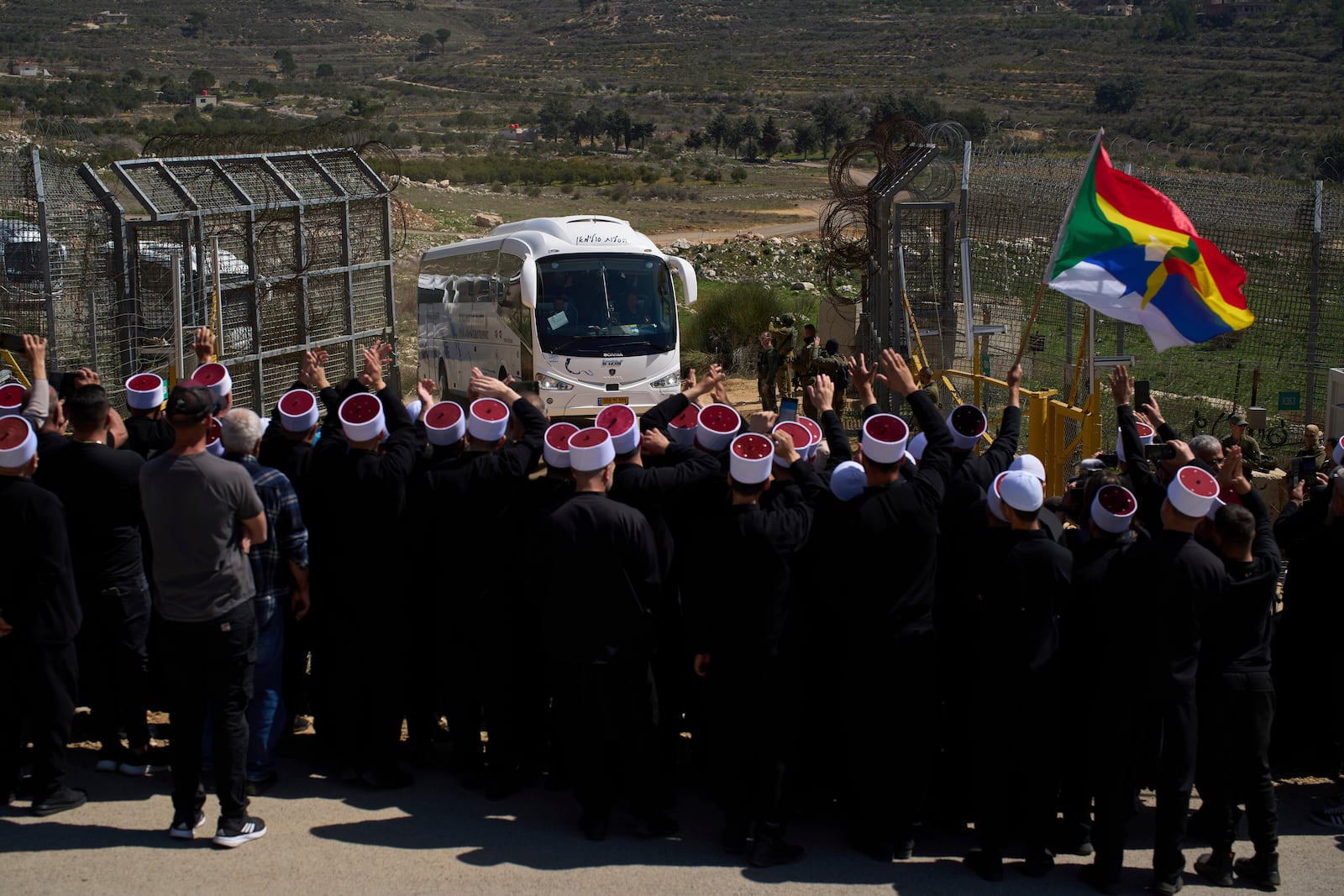 Buses carrying members of the Syrian Druze community are welcomed by Druze clerics at the border with Syria, as they enter into the village of Majdal Shams, in the Israeli-controlled Golan Heights, Friday, March 14, 2025. (AP Photo/Leo Correa)