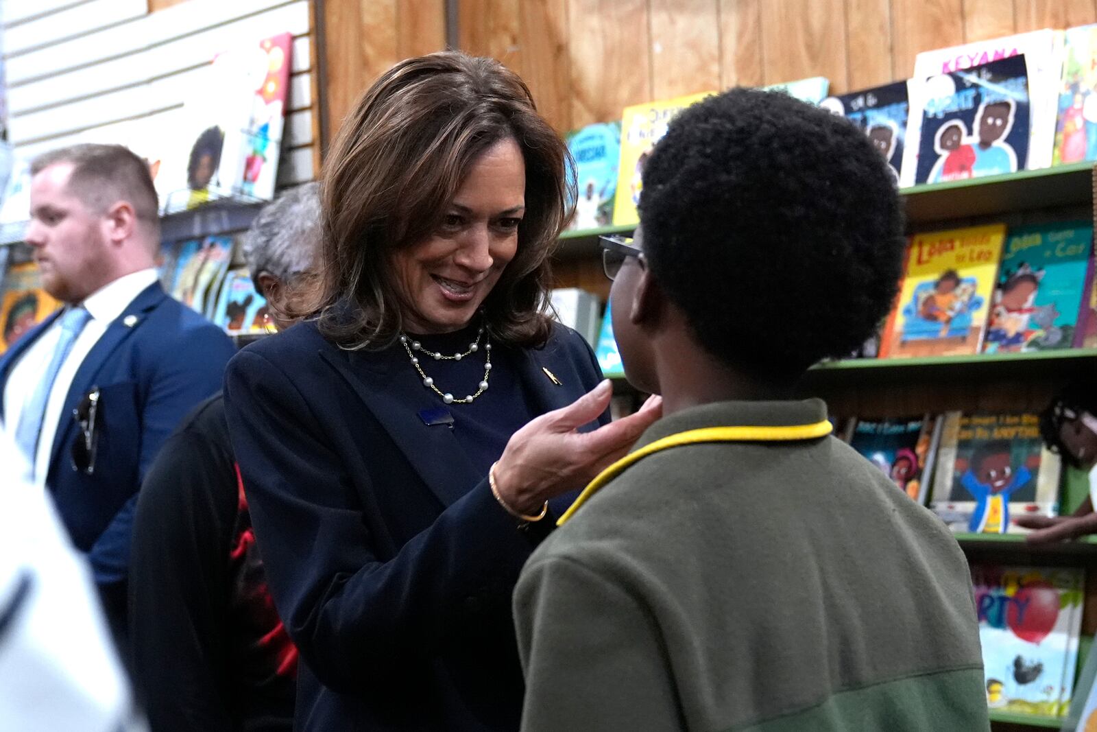 Democratic presidential nominee Vice President Kamala Harris, left, greets a young man at Hakim's Bookstore and Gift Shop during a campaign stop, Sunday, Oct. 27, 2024, in Philadelphia. (AP Photo/Susan Walsh)