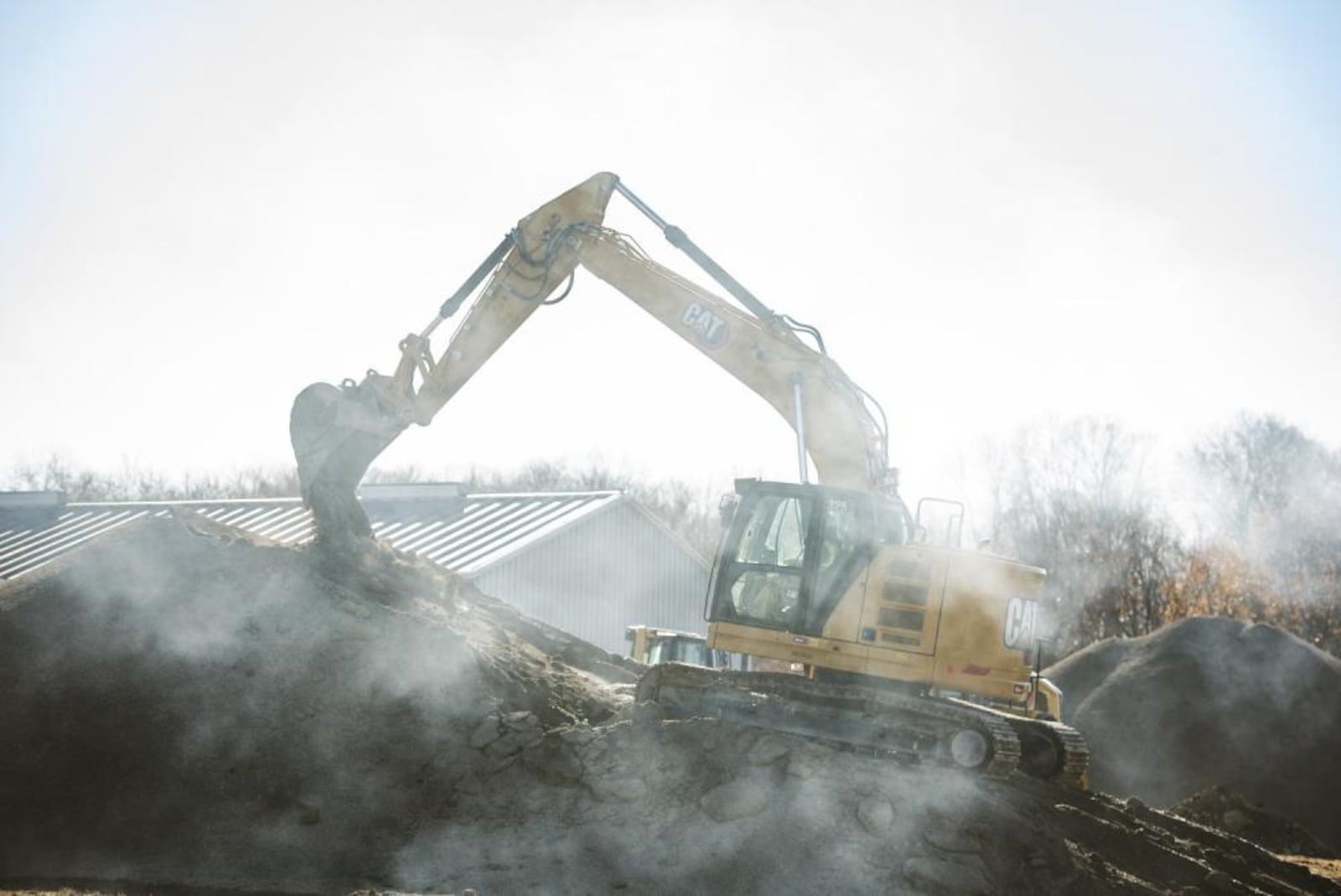 A worker uses an excavator Nov. 21 to prep a gravel pile at Wright-Patterson Air Force Base. The 450-foot trench being dug is part of an Area B construction project designed to help remove substances previously used in firefighting from groundwater. (U.S. Air Force photo by Hannah Carranza)