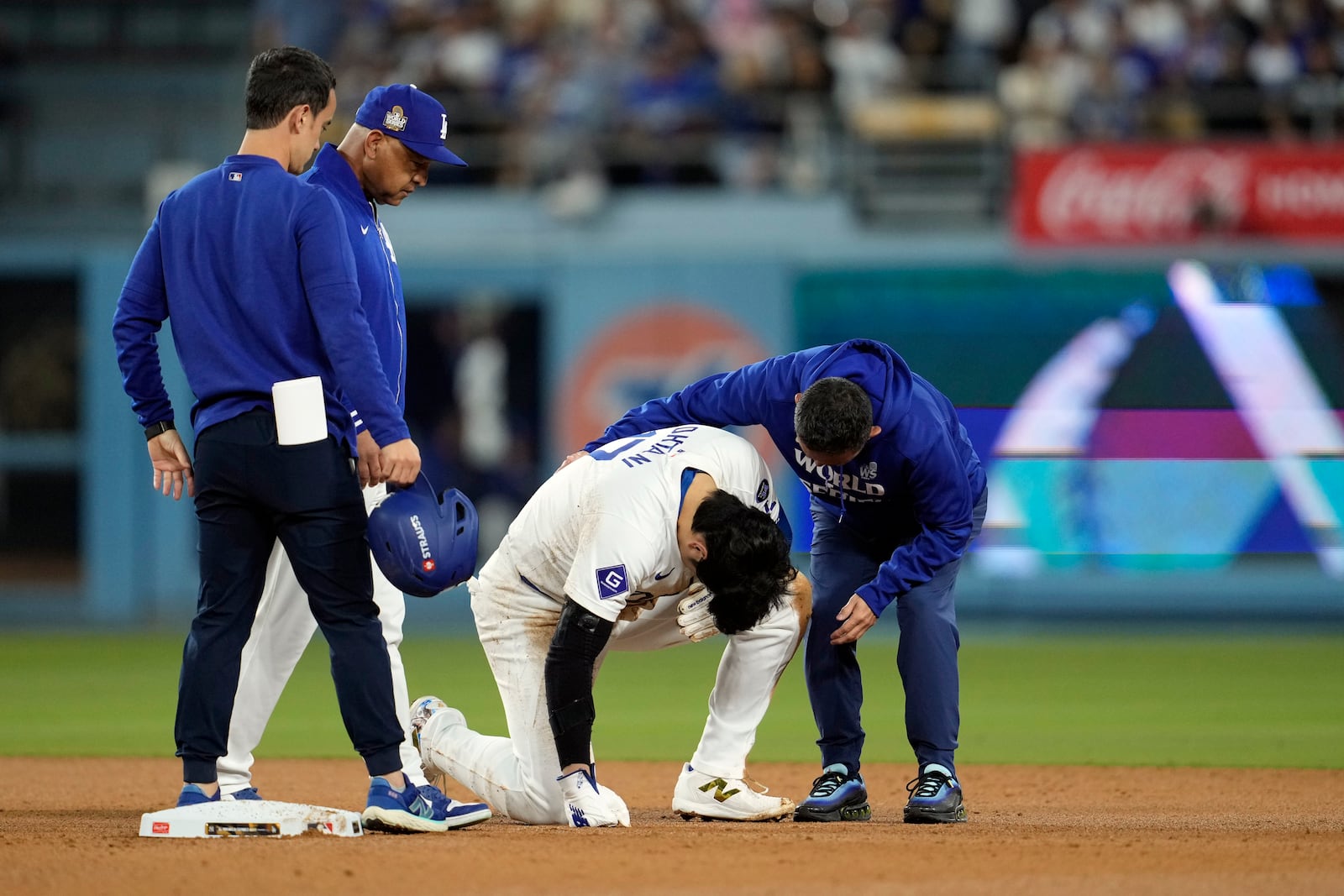 Los Angeles Dodgers' Shohei Ohtani, bottom, is helped after being injured while trying to steal second base against the New York Yankees during the seventh inning in Game 2 of the baseball World Series, Saturday, Oct. 26, 2024, in Los Angeles. (AP Photo/Godofredo A. Vásquez)