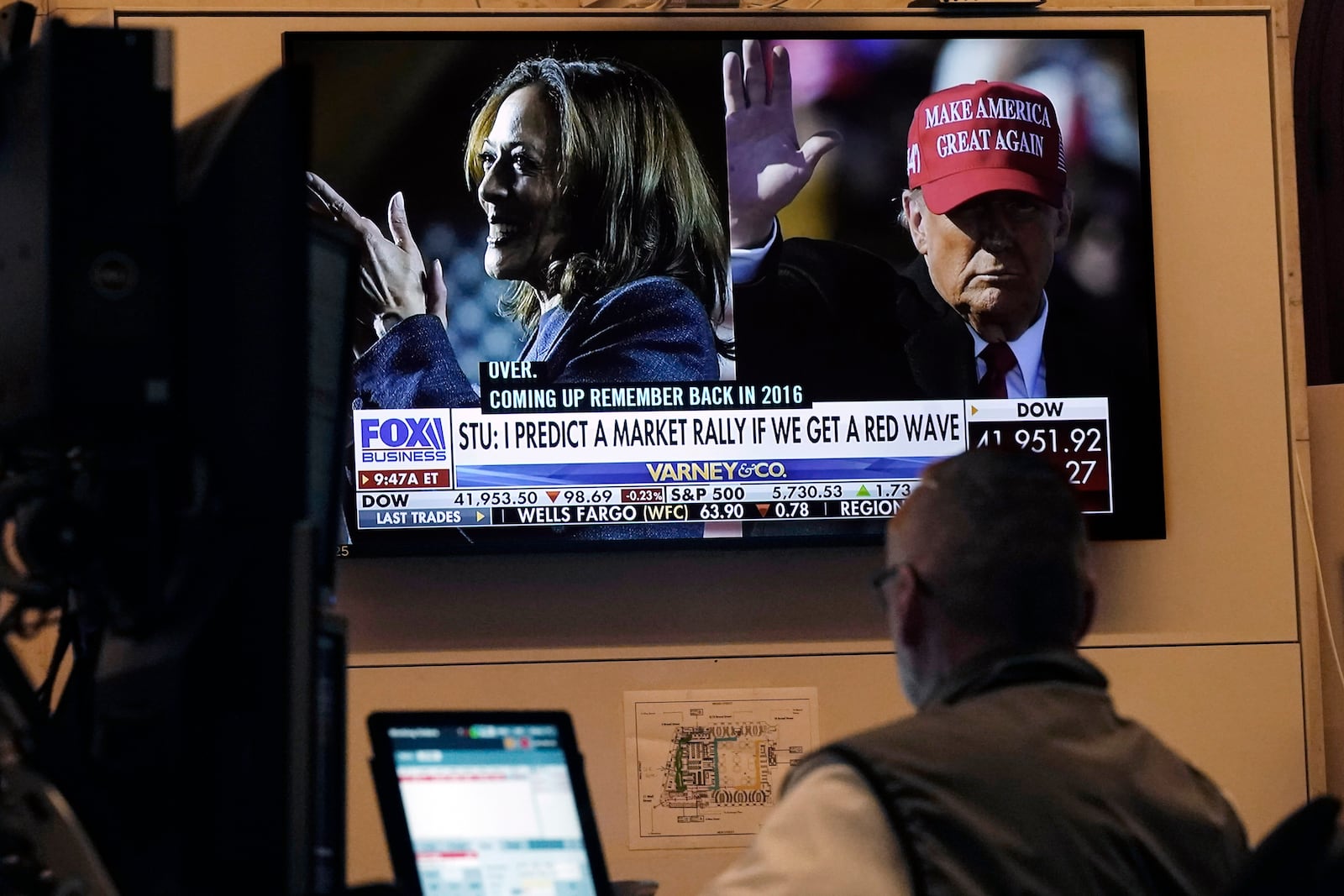 A screen on the floor of the New York Stock Exchange, Monday, Nov. 4, 2024 shows a broadcast talking about Kamala Harris and Donald Trump. (AP Photo/Richard Drew)