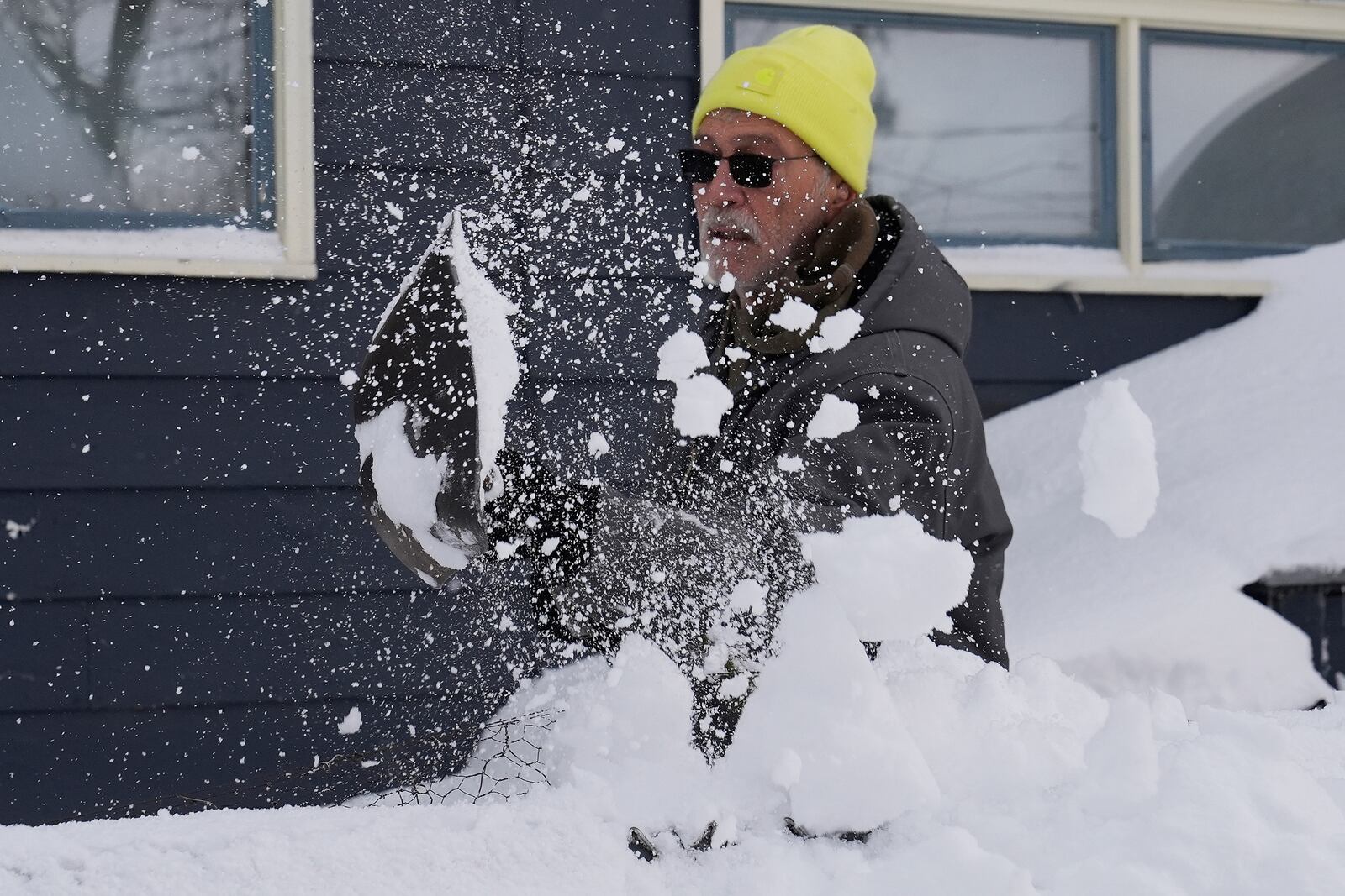 Ron Colby clears snow from a dog run at his home, Monday, Dec. 2, 2024, in Geneva-on-the-Lake, Ohio. (AP Photo/Sue Ogrocki)