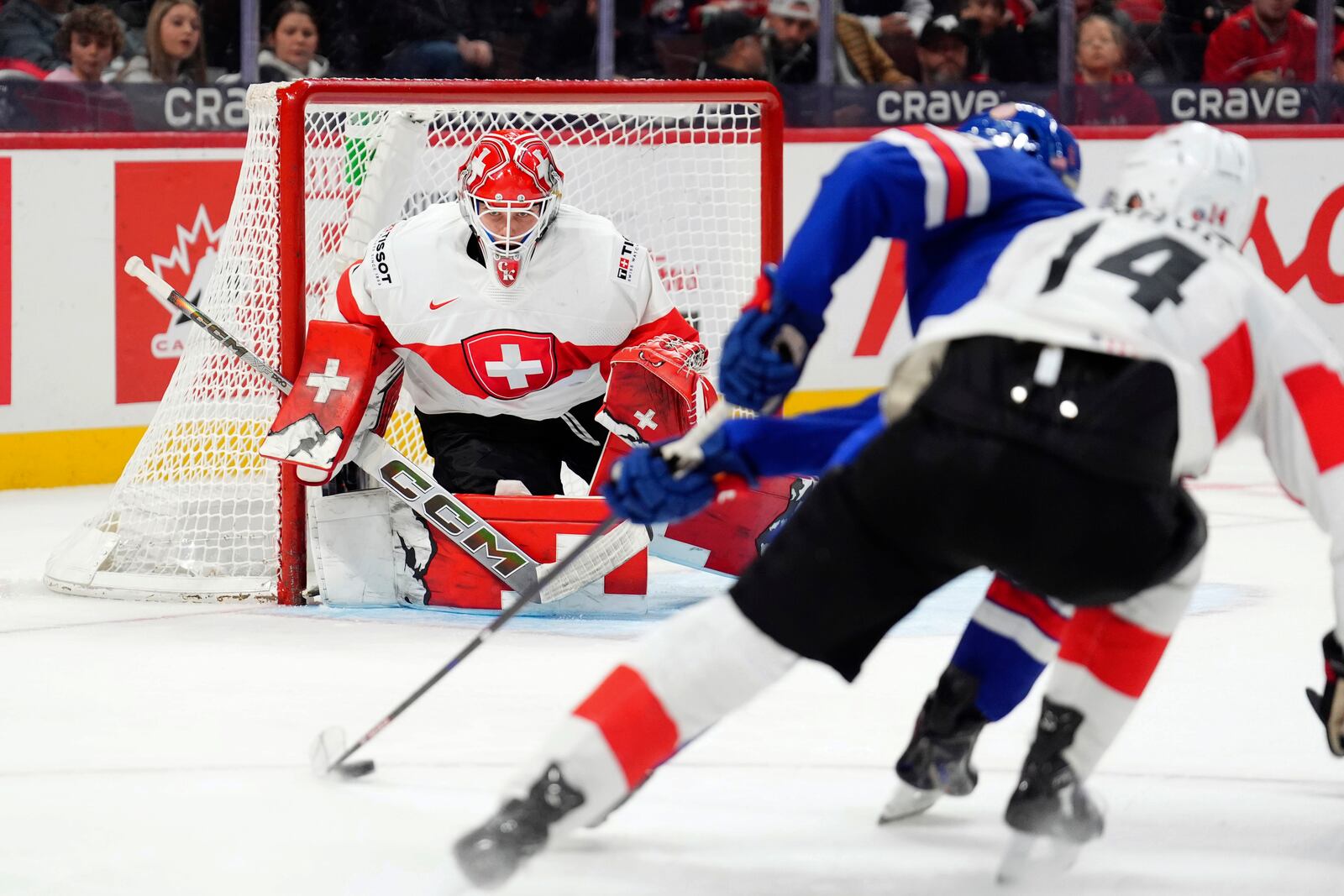 USA forward Ryan Leonard (9) moves towards the net as Switzerland goaltender Christian Kirsch (1) keeps an eye on the puck and defenseman Nils Rhyn (14) defends the first period of a quarterfinal match at the IIHF World Junior Hockey Championship in Ottawa, Ontario Thursday, Jan. 2, 2025. (Sean Kilpatrick/The Canadian Press via AP)