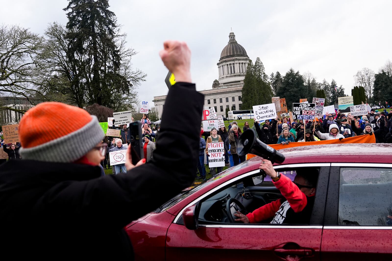 A driver sticks a bullhorn out their window and honks in support as people gather to protest against the Trump administration and Project 2025 near the Washington State Capitol building Wednesday, Feb. 5, 2025, in Olympia, Wash. (AP Photo/Lindsey Wasson)