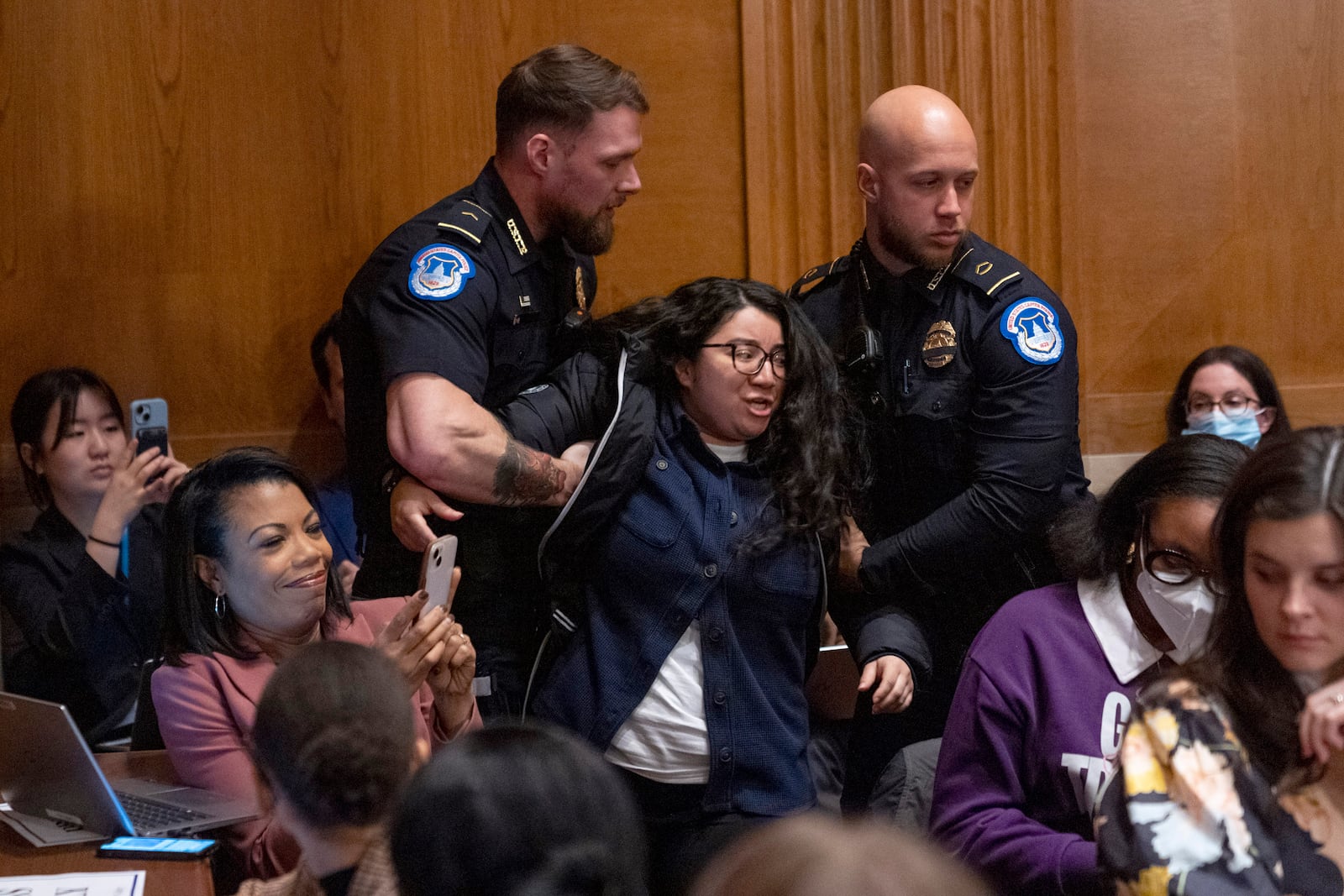 A protester is removed while calling out for protections for transgender and immigrant students, during a nomination hearing for Linda McMahon, President Donald Trump's nominee for Secretary of Education, at a Health, Education, and Labor Committee hearing, Thursday, Feb. 13, 2025, in Washington. (AP Photo/Jacquelyn Martin)