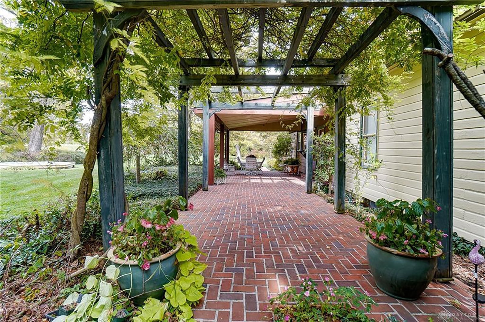 The home has a covered rear brick paver patio and wood pergola