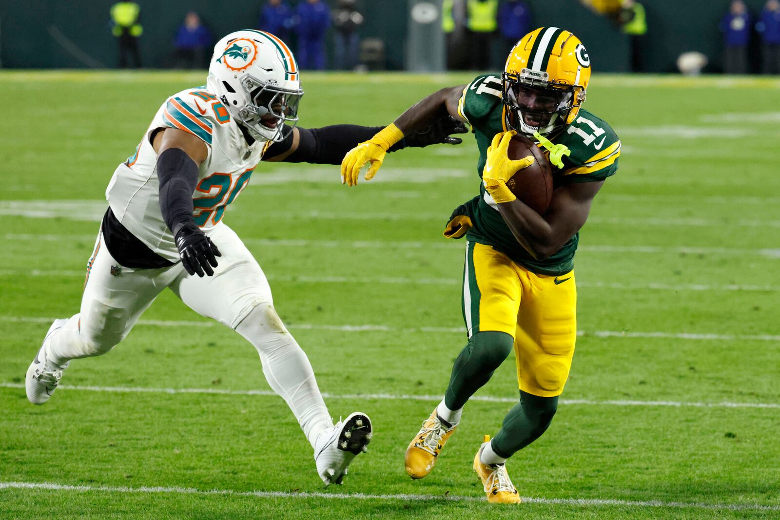 Green Bay Packers wide receiver Jayden Reed (11) runs from Miami Dolphins linebacker Jordyn Brooks (20) during a 12-yard touchdown reception in the first half of an NFL football game Thursday, Nov. 28, 2024, in Green Bay, Wis. (AP Photo/Mike Roemer)