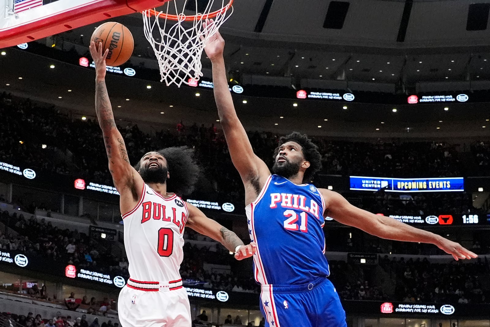 Chicago Bulls guard Coby White, left, drives to the basket against Philadelphia 76ers center Joel Embiid during the second half of an NBA basketball game in Chicago, Sunday, Dec. 8, 2024. (AP Photo/Nam Y. Huh)