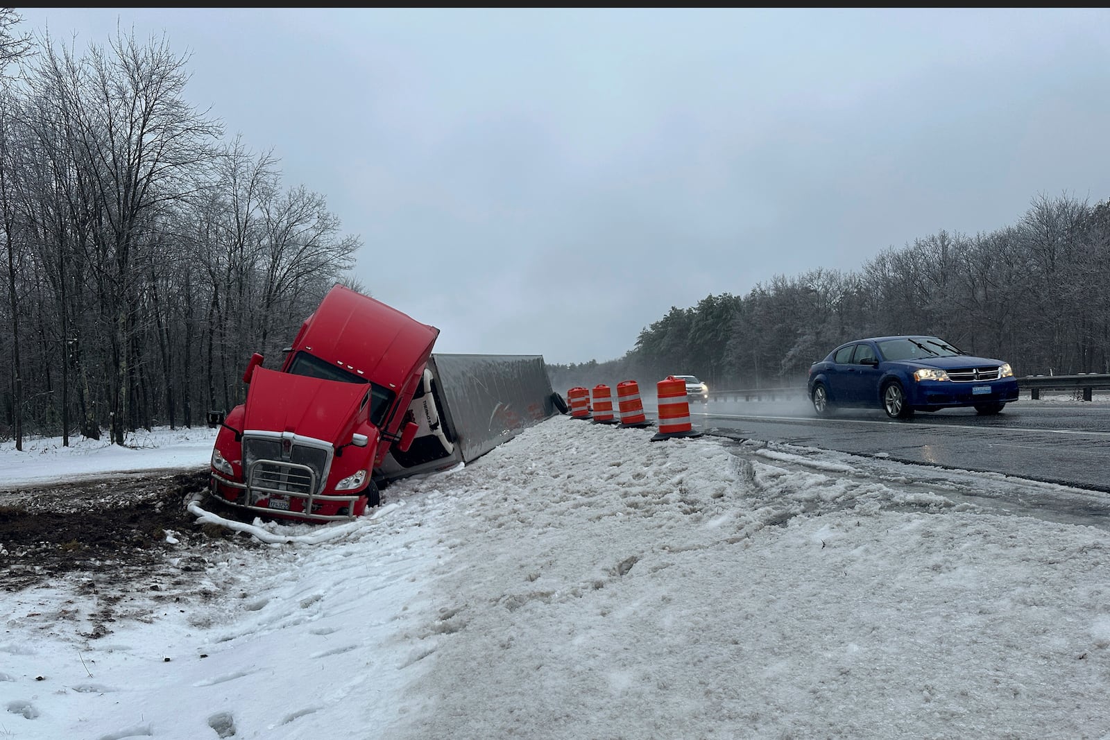 A tractor-trailer hauling a load of oranges sits on the side of the road after sliding off the Maine Turnpike early on Wednesday, Dec. 11, 2024, in New Gloucester, Maine. (AP Photo/David Sharp)