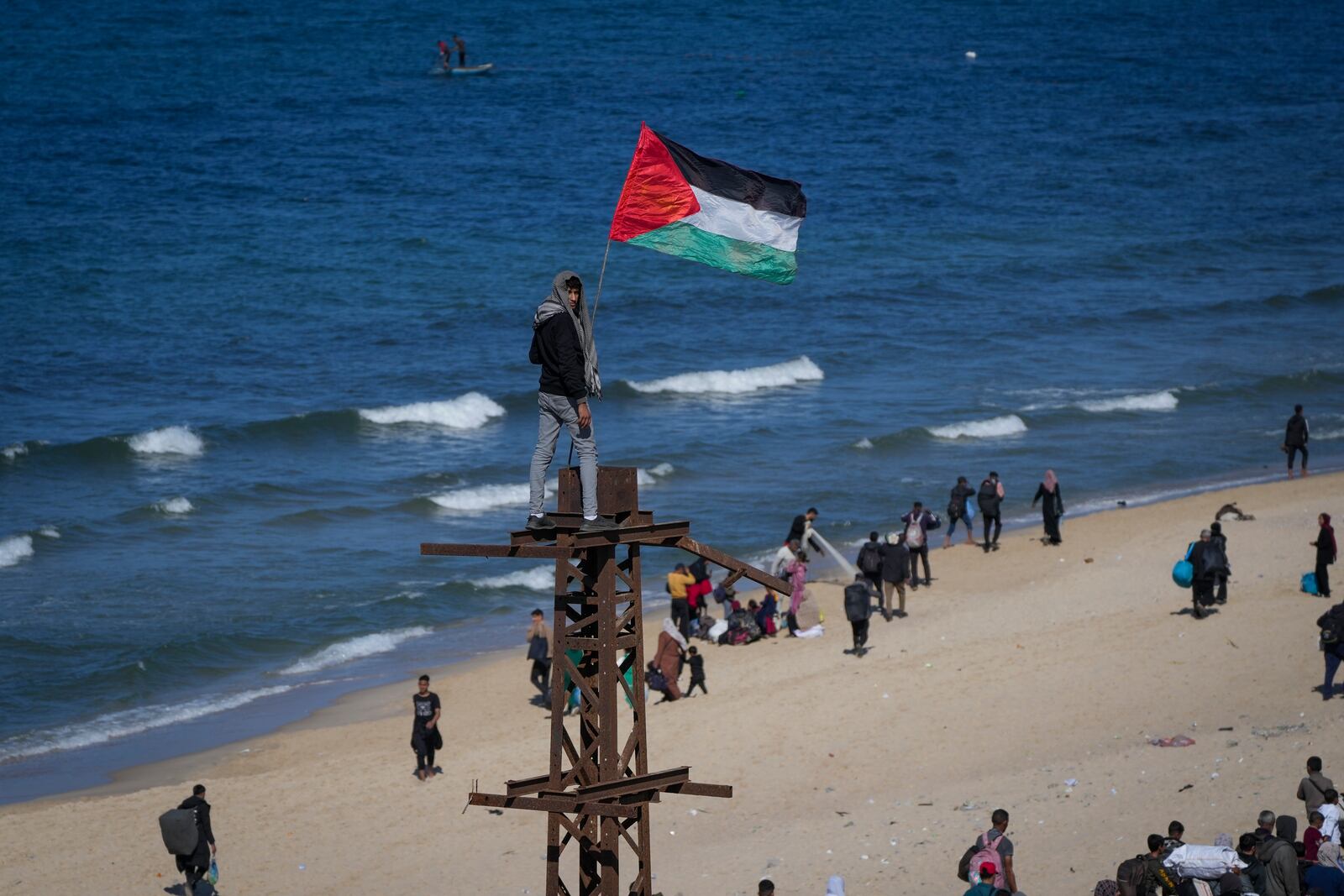 A boy holds a Palestinian flag as displaced Palestinians return to their homes in the northern Gaza Strip, following Israel's decision to allow thousands of them to go back for the first time since the early weeks of the 15-month war with Hamas, Monday, Jan. 27, 2025. (AP Photo/Abdel Kareem Hana)