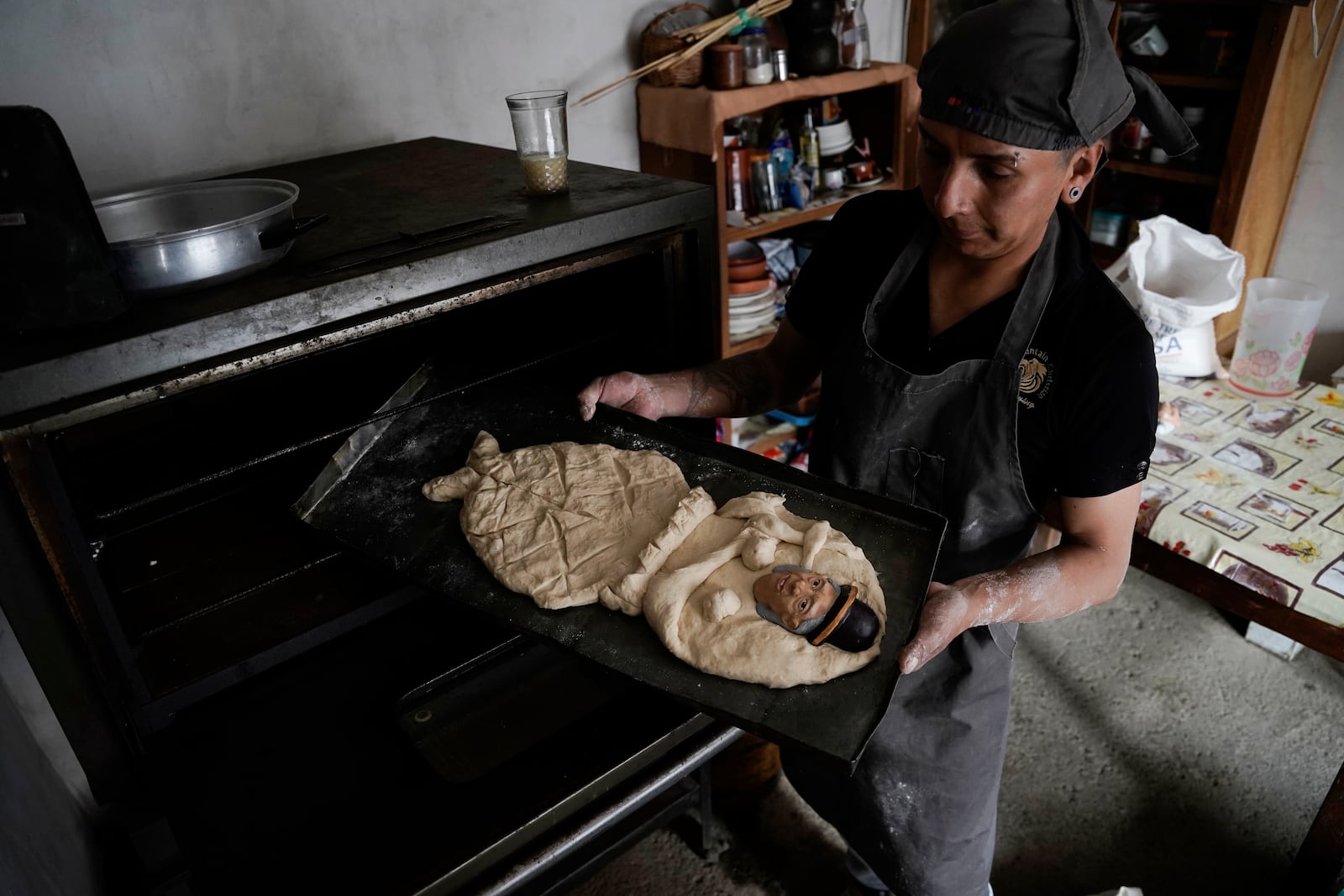 Artisan William Luna places a piece of tantawawa bread with a mask of his grandmother in the oven during Day of the Dead celebrations in La Paz, Bolivia, Thursday, Oct. 31, 2024. (AP Photo/Freddy Barragan)