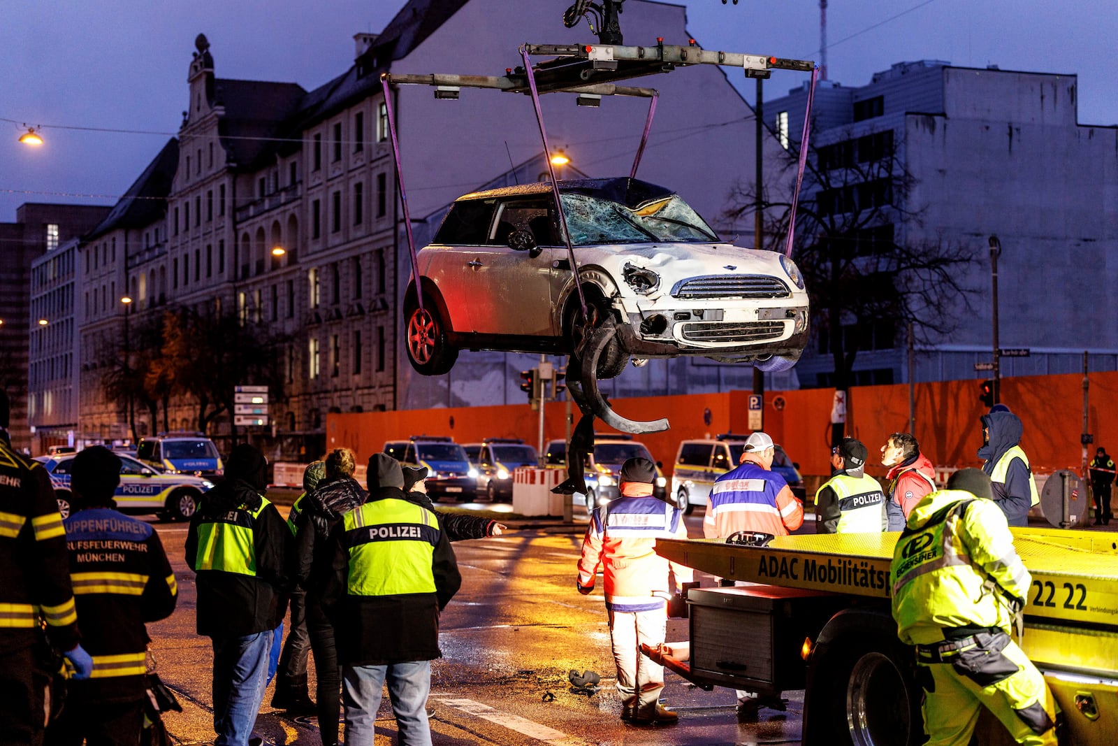 A car is lifted onto a tow truck at the scene where a driver drove a car into a labor union demonstration in Munich, Germany, Thursday Feb. 13, 2025. (Matthias Balk/dpa via AP)