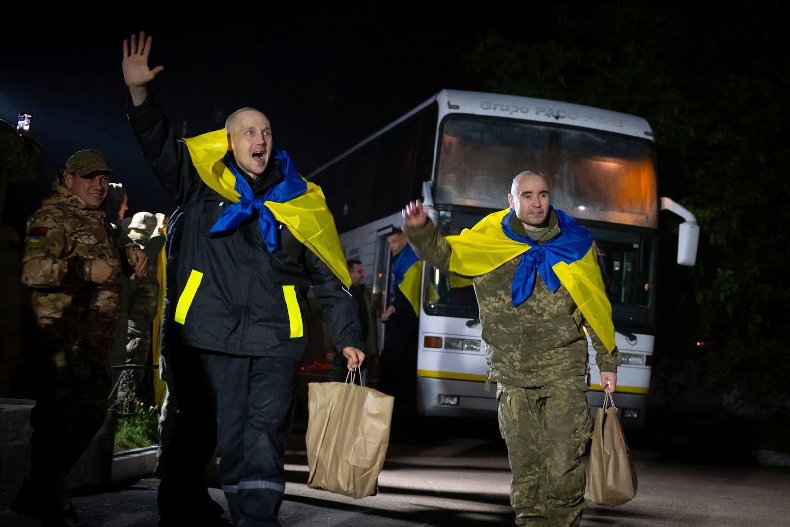 In this photo provided by the Press Service of the President of Ukraine on Oct. 19, 2024, Ukrainian servicemen shout, "Glory to Ukraine," with National flags after returning from captivity during a POWs exchange in an undisclosed location, Ukraine. (Press Service of the President of Ukraine via AP)