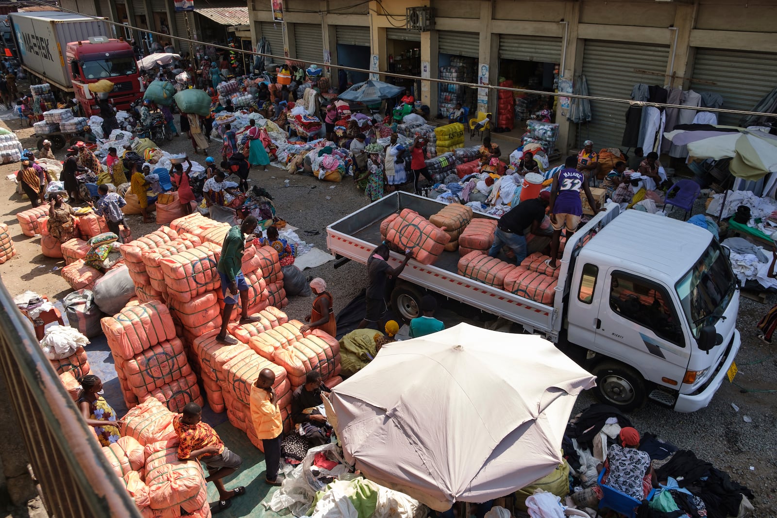 People offload bales of Second-hand clothes from a truck at Kantamanto market, one of the world's largest second-hand clothes markets in Accra, Ghana, Thursday, Oct. 31, 2024. (AP Photo/Misper Apawu)