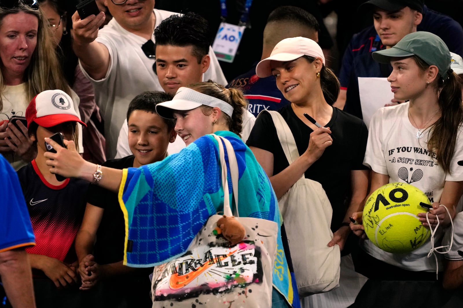 Mirra Andreeva of Russia takes a selfie with spectators following her first round win over Marie Bouzkova of the Czech Republic at the Australian Open tennis championship in Melbourne, Australia, Sunday, Jan. 12, 2025. (AP Photo/Ng Han Guan)