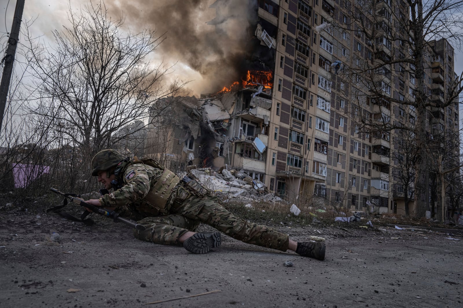 FILE - A Ukrainian police officer takes cover in front of a burning building that was hit in a Russian airstrike in Avdiivka, Ukraine, Friday, March 17, 2023. (AP Photo/Evgeniy Maloletka, File)