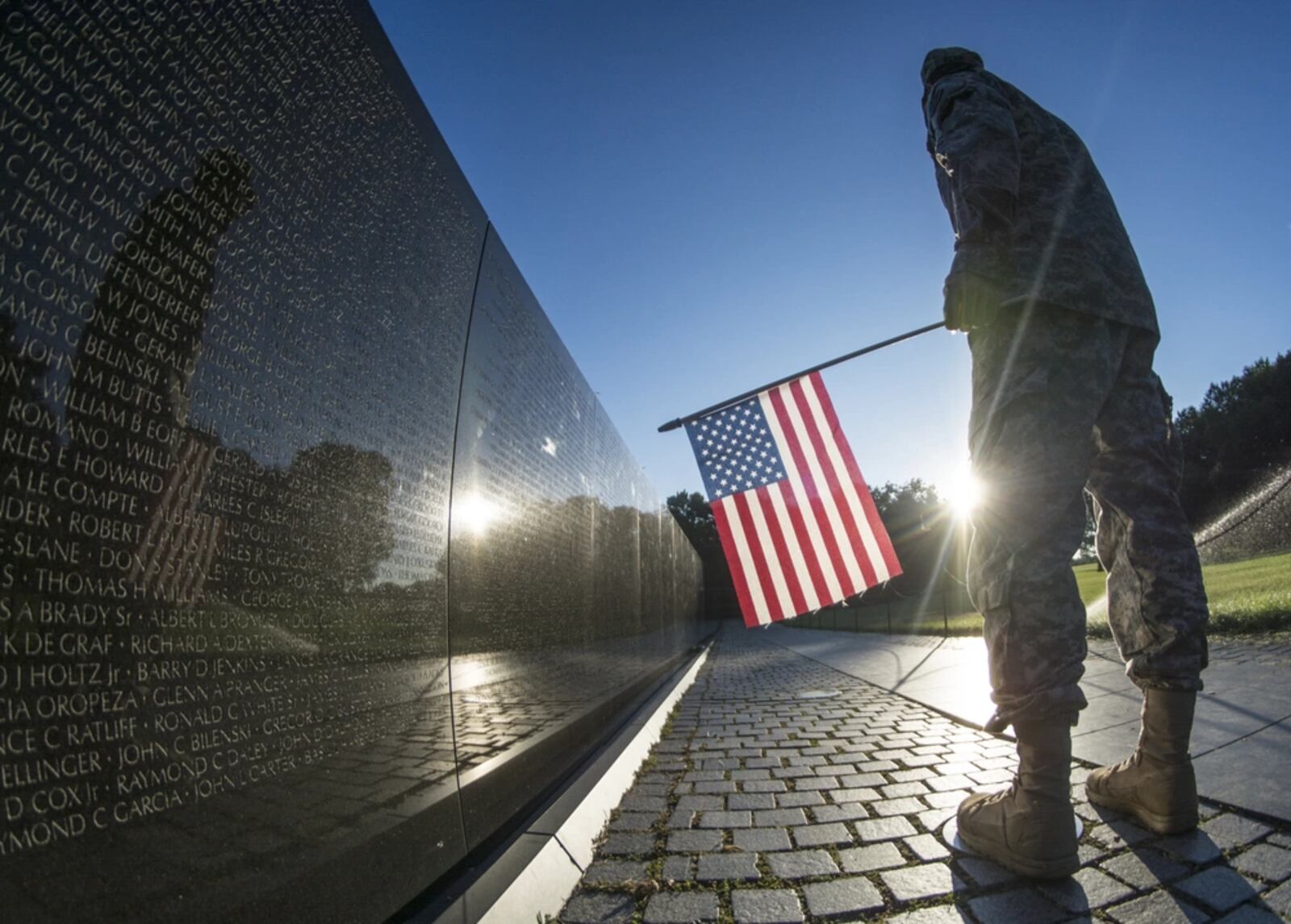 A U.S. Army Reserve soldier reads some of the 58,307 names etched into "The Wall" of the Vietnam Veterans Memorial in Washington, D.C. as the sun rises July 22, 2015. (U.S. Army photo by Sgt. Ken Scar)