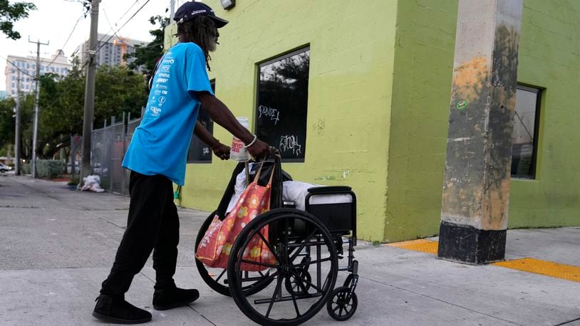 Robert Robinson, 61, who is homeless, pushes his belongings down the street on the first day of a statute that took effect, making it illegal in Florida to sleep on sidewalks, in parks, on beaches or in other public spaces — one of the country's strictest anti-homelessness laws, Tuesday, Oct. 1, 2024, in Fort Lauderdale, Fla. (AP Photo/Lynne Sladky)