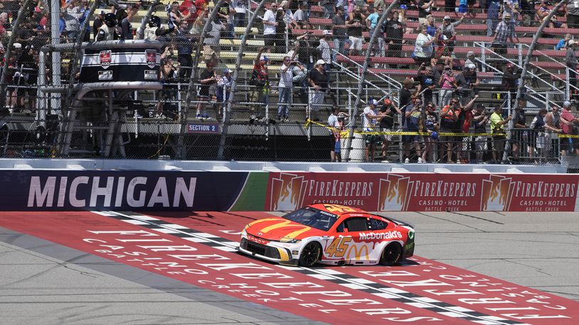 Tyler Reddick takes the checker flag after winning a NASCAR Cup Series auto race at Michigan International Speedway, Monday, Aug. 19, 2024, in Brooklyn, Mich. (AP Photo/Carlos Osorio)