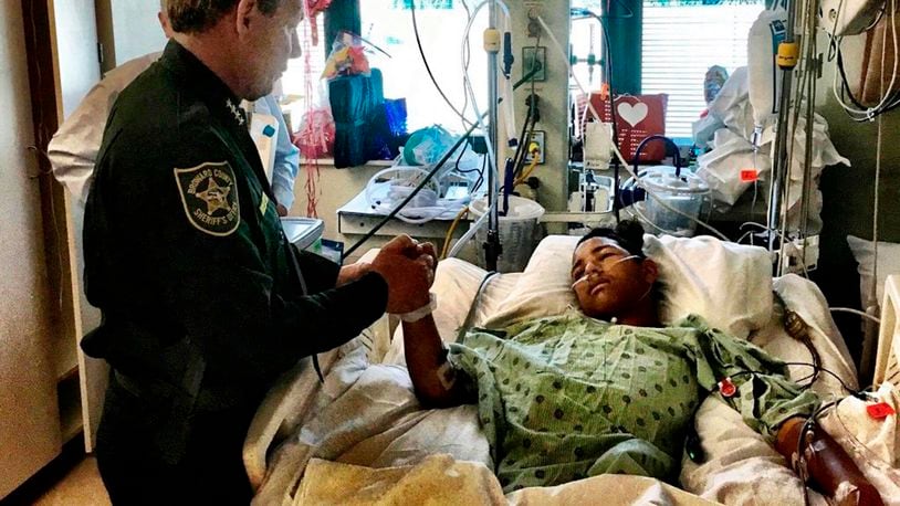 In this photo provided by the Broward County Sheriff's Office on Sunday, Feb. 18, 2018, Sheriff Scott Israel, holds the hand of Anthony Borges, 15, a student at Marjory Stoneman Douglas High School. Borges, the most severely wounded survivor of the 2018 massacre at Parkland's Marjory Stoneman Douglas High School, now owns shooter Nikolas Cruz's name and Cruz cannot give any interviews without his permission, under a settlement reached in a lawsuit, his attorney said Thursday, June 27, 2024. (Broward County Sheriff's Office via AP)