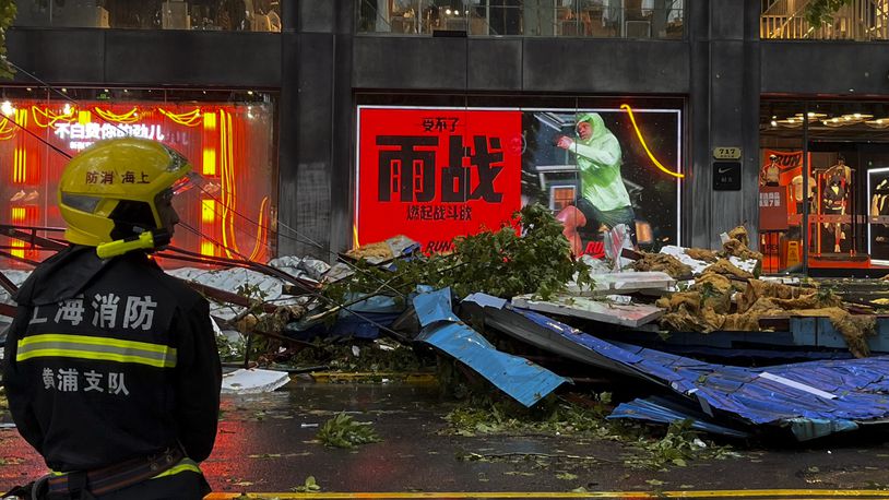 A firefighter stands near debris along a business street in the aftermath of Typhoon Bebinca in Shanghai, China, Monday, Sept. 16, 2024. (Chinatopix Via AP)