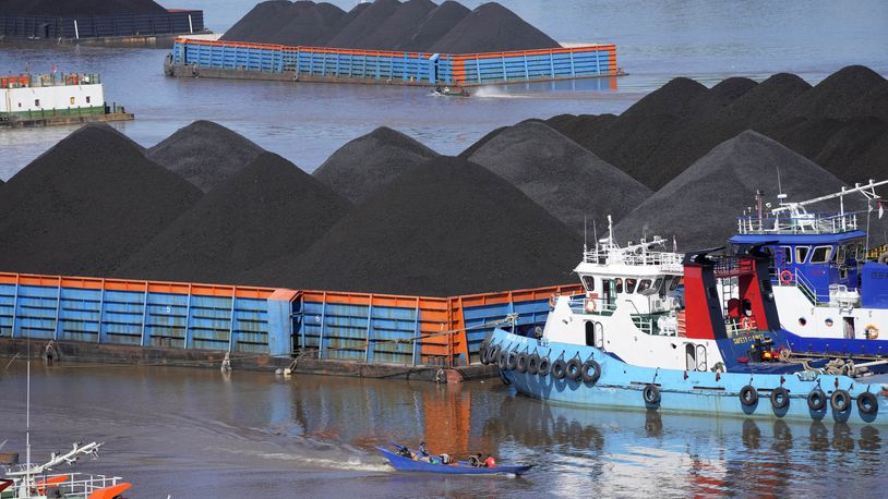 FILE- Boats cruise near barges fully loaded with coal on the Mahakam river in Samarinda, East Kalimantan, Indonesia, on Dec. 19, 2022. (AP Photo/Dita Alangkara, File)